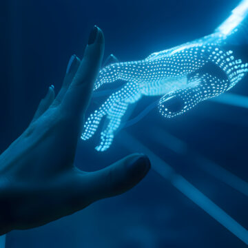 Contact between a cyber hand hand a human hand - Technologies and artificial intelligence concept O futuro do trabalho entre humanos e máquinas: a era dos híbridos chegou